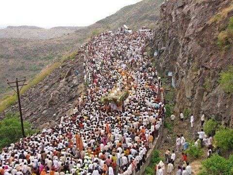 Warkaris carrying Palkhi under cloudy skies in Maharashtra’s Ghat region during orange alert.