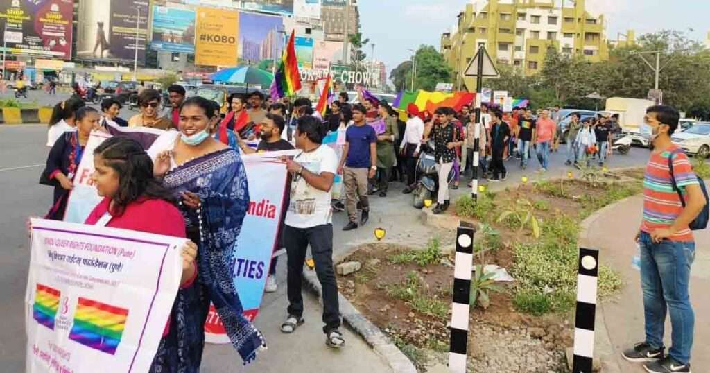 Crowd at Pune Pride Walk 2025 holding rainbow flags and signs promoting LGBTQ+ equality.